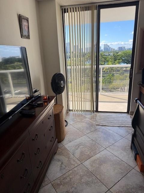 Ceramic tile flooring, sliding glass door with vertical blinds, and a private balcony featuring a skyline and landscape backdrop