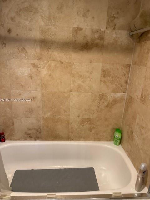 Bathtub with white enamel finish and floor-to-ceiling square tile wall surround