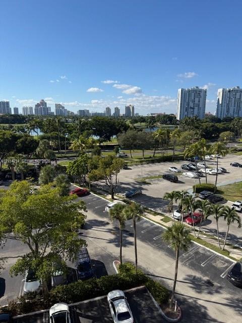 Elevated exterior perspective featuring mature palm trees, landscaped green space, and a panoramic cityscape backdrop Elevated exterior perspective featuring mature palm trees, landscaped green space, and a panoramic cityscape backdrop