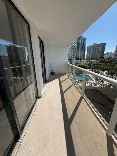 Covered outdoor balcony featuring a concrete floor, glass-paneled railing, and dual sliding glass door access