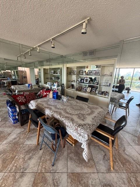 Floor-to-ceiling mirrored walls, built-in display cabinetry with glass shelving, tile flooring, and adjustable track lighting