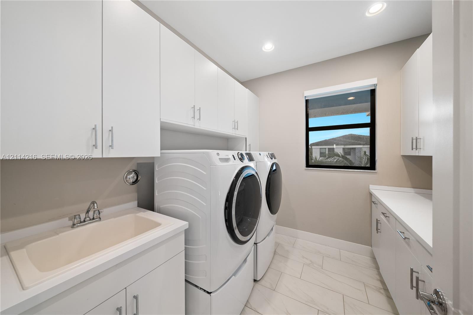 Laundry room featuring white cabinetry, a composite utility sink, quartz countertops, recessed lighting, and tile flooring