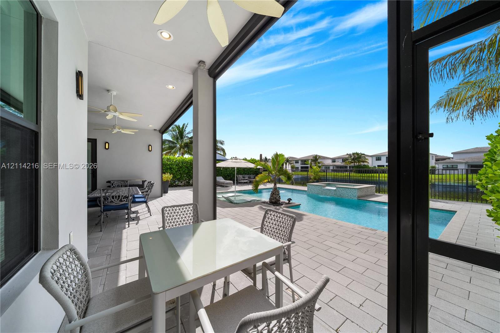 Covered patio featuring recessed lighting and ceiling fans, leading to a paver pool deck, swimming pool, and integrated spa