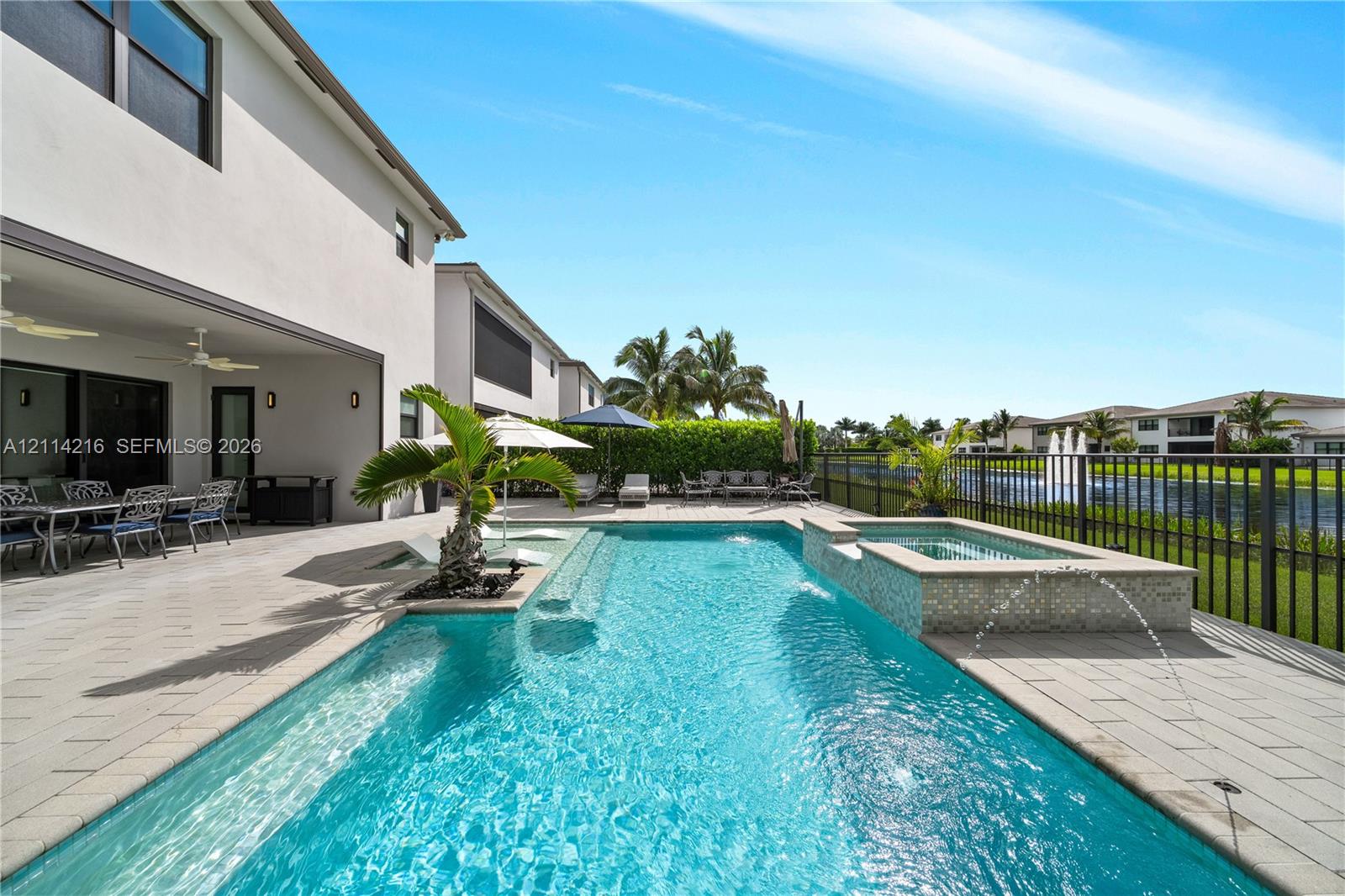 Covered patio with paver flooring, custom in-ground swimming pool, elevated spa with tile finish, and water feature