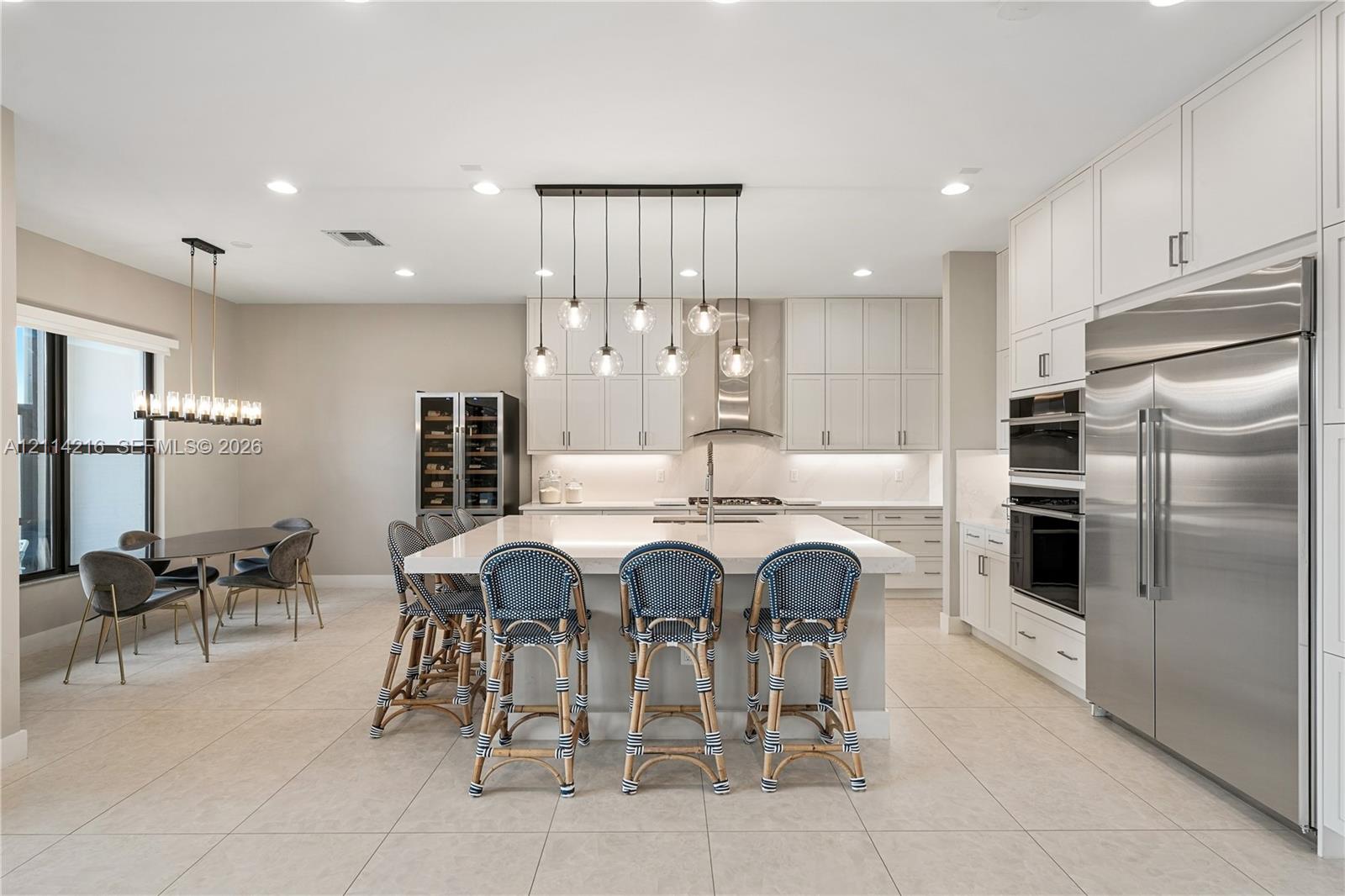 Kitchen featuring flat-panel cabinetry, a central island with a quartz countertop, professional-grade stainless steel appliances, a built-in wine refrigerator, and multi-light pendant fixtures