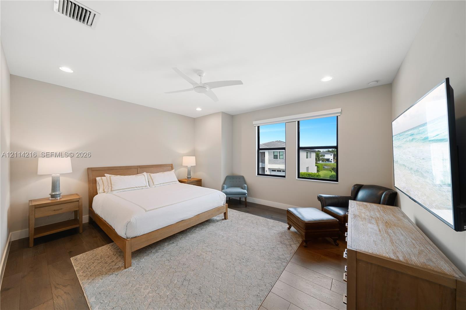 Spacious room featuring wood-finish flooring, recessed lighting, a white ceiling fan, and large windows with black frames