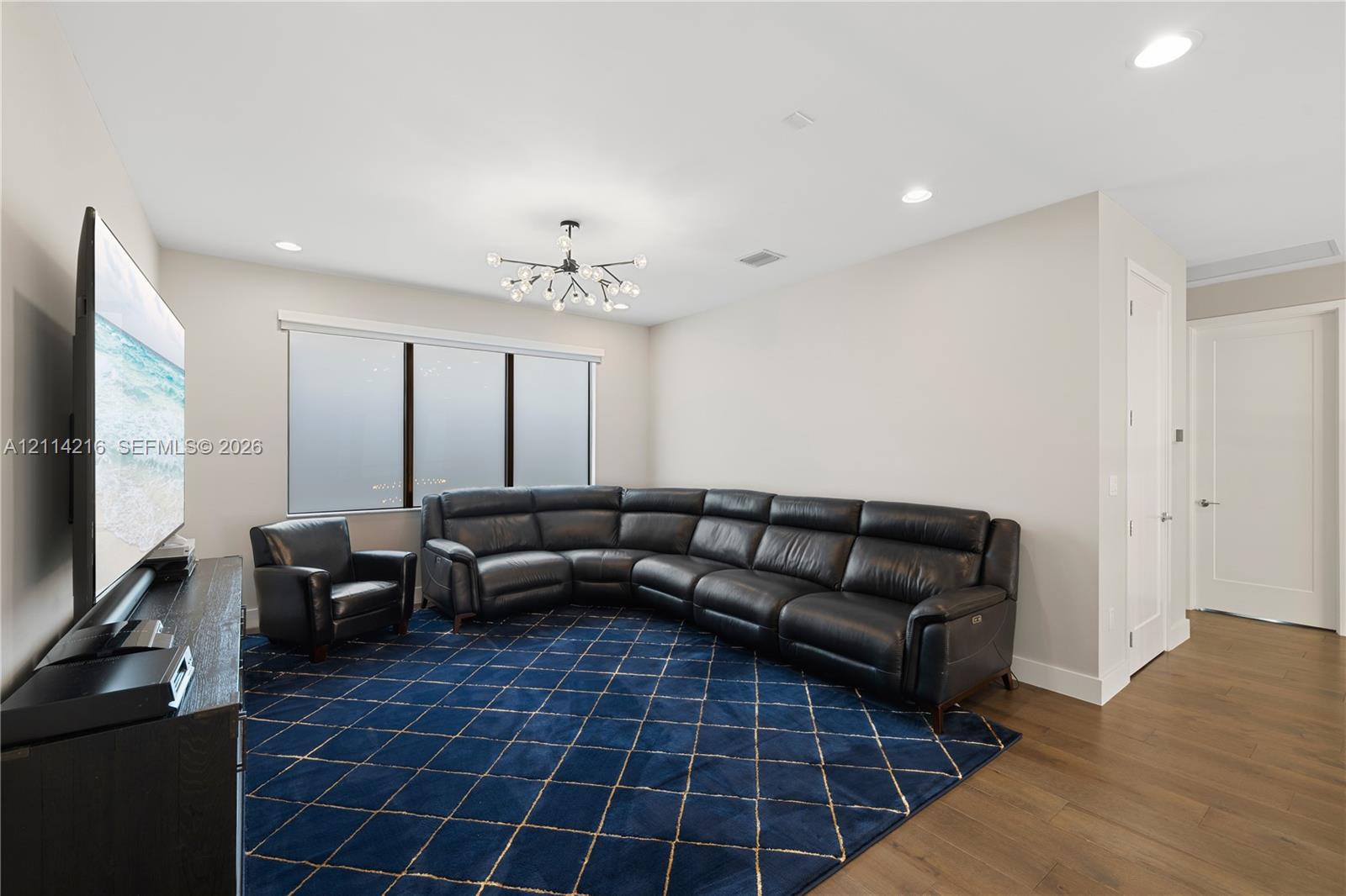 Room featuring wood-finish flooring, recessed lighting, and a multi-arm modern chandelier