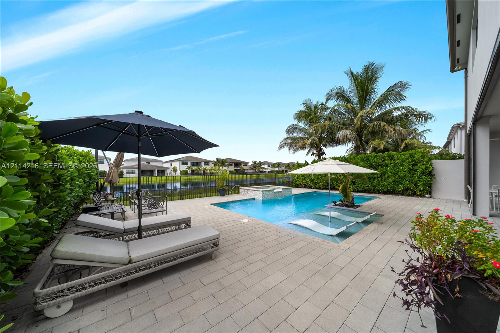 Screened swimming pool and spa with stone paver decking, finished with perimeter landscaping and water frontage