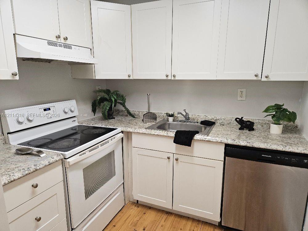 Kitchen featuring white shaker-style cabinetry, stone-finish countertops, stainless steel undermount sink, integrated range, and stainless steel dishwasher