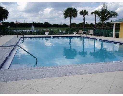 Swimming pool with a paved deck, metal railings, and perimeter fencing