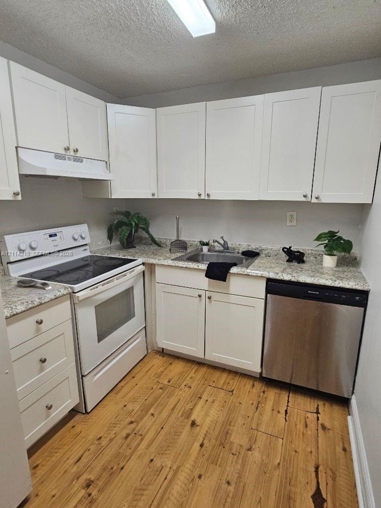 Kitchen featuring white shaker-style cabinetry, stone-finish countertops, wood-finish flooring, and stainless steel dishwasher