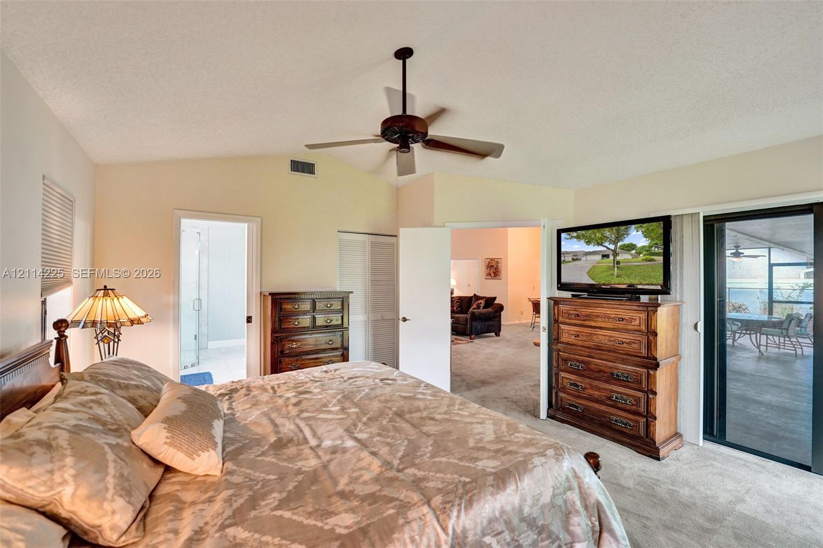 Vaulted ceiling featuring a central blade-style ceiling fan and sliding glass doors providing access to the exterior