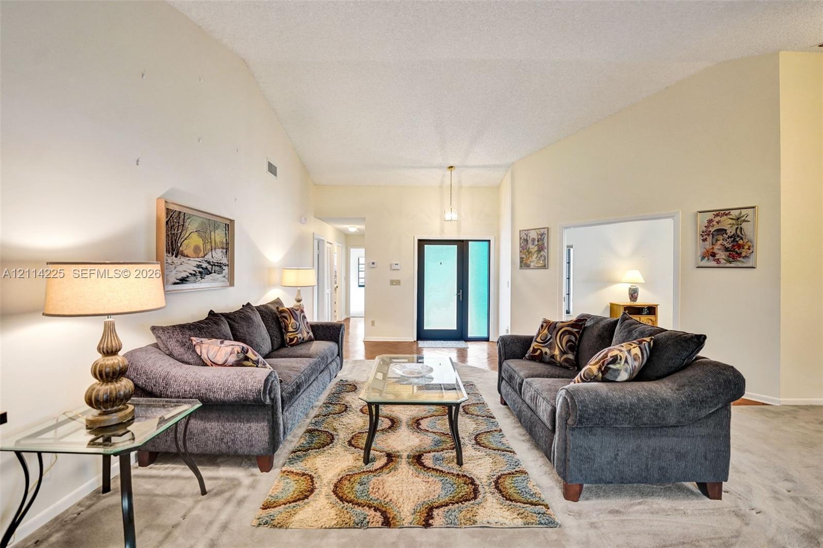 Living area featuring vaulted ceilings, a glass-panel entry door, and neutral wall tones