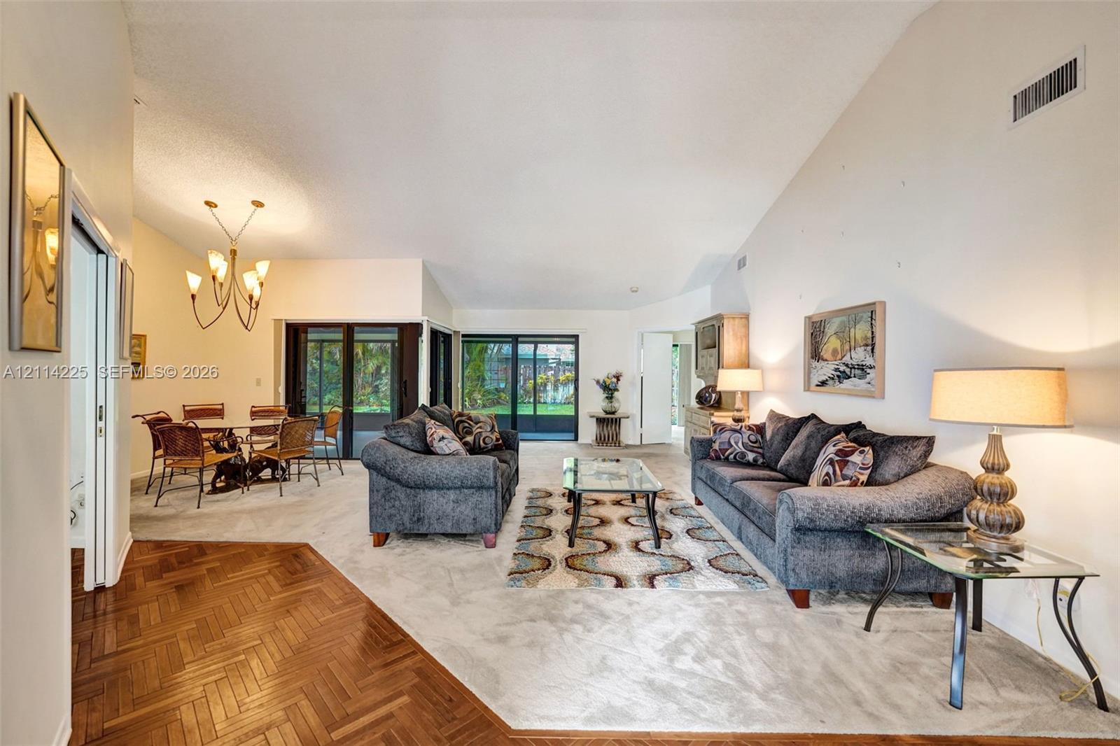 Vaulted ceilings, parquet wood flooring, and multi-panel sliding glass doors providing outdoor access