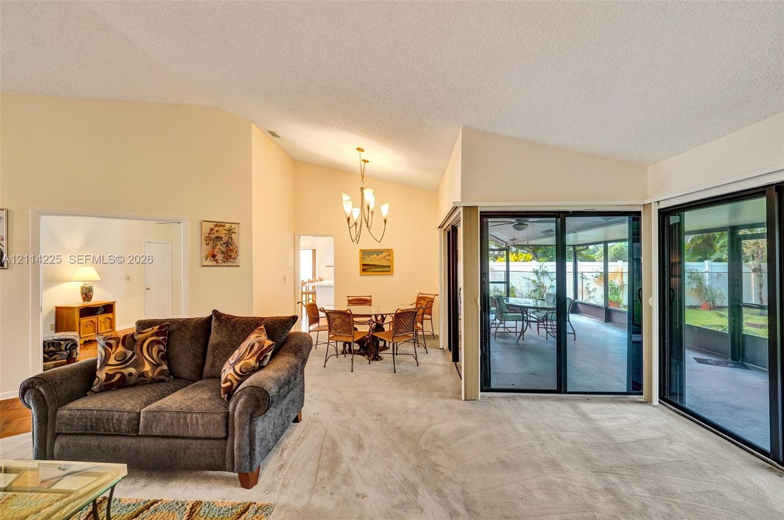 Vaulted ceilings with recessed lighting, multi-panel sliding glass doors, and carpeted flooring