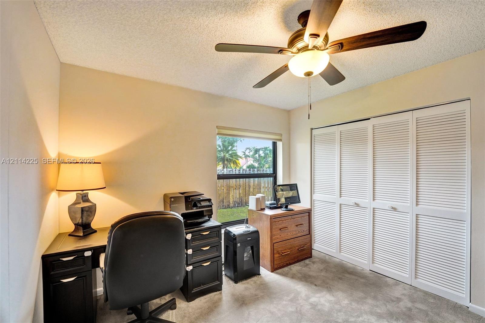 Room featuring a textured ceiling, a four-blade ceiling fan with an integrated light fixture, and white louvered closet doors