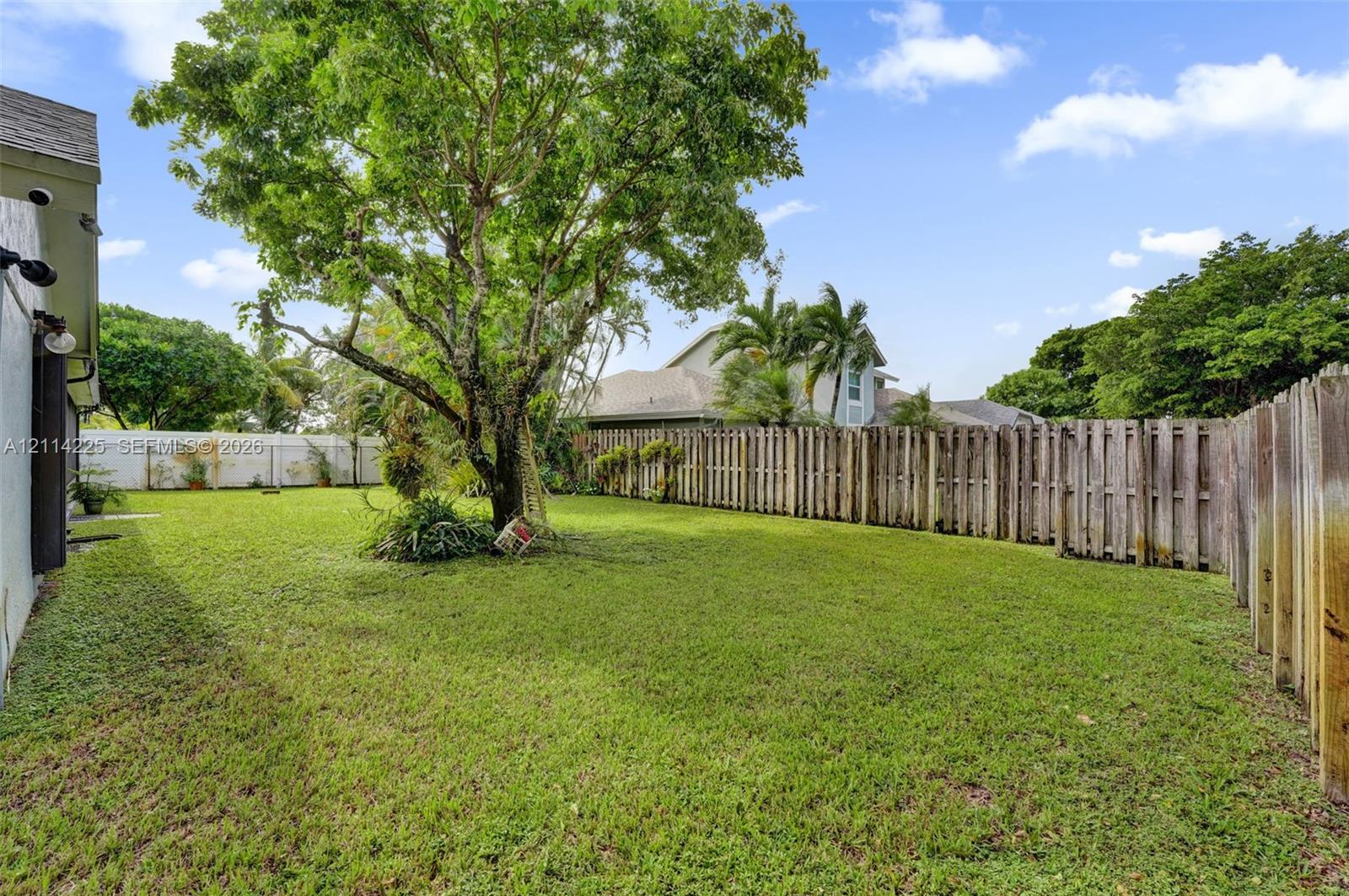 Expansive backyard featuring a fenced perimeter, mature tree, and open green space