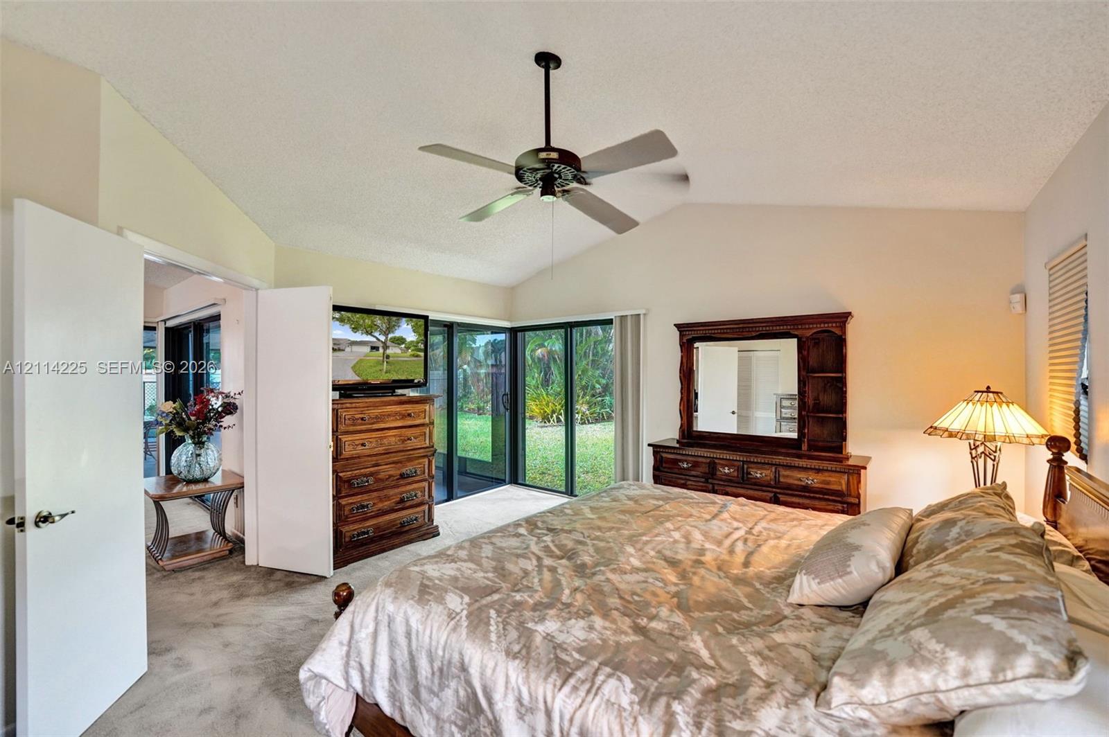 Vaulted ceilings featuring a centrally mounted ceiling fan and sliding glass doors providing external access