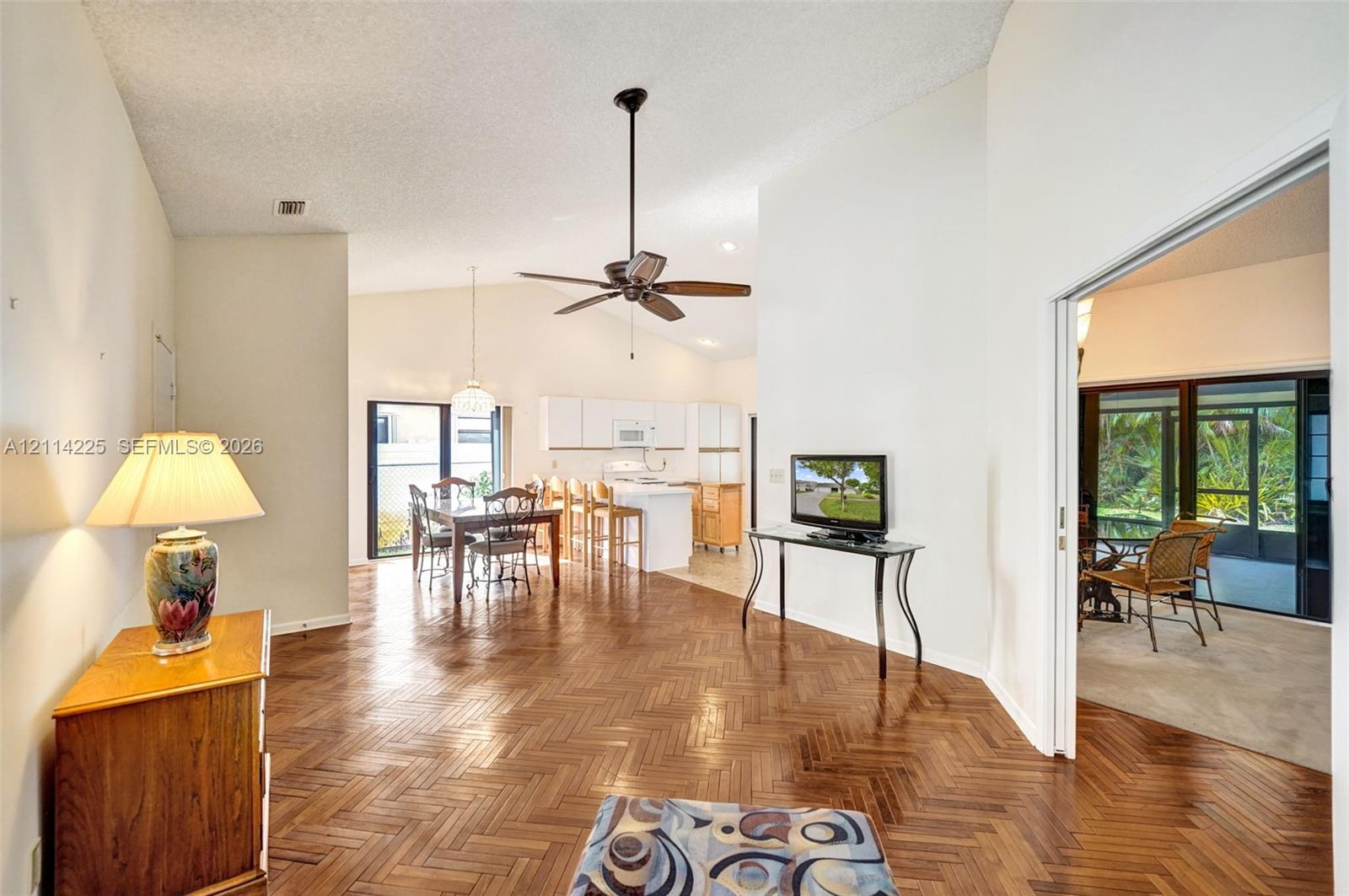Herringbone-patterned wood flooring, vaulted ceilings, and a central ceiling fan