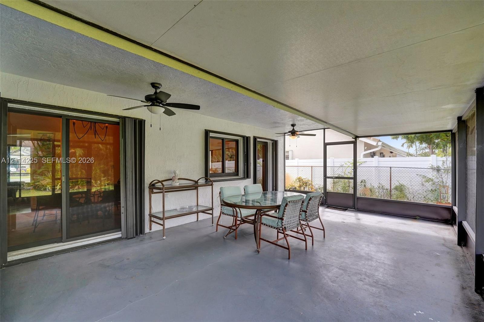 Covered lanai featuring a concrete floor, two ceiling fans, and a screened-in enclosure