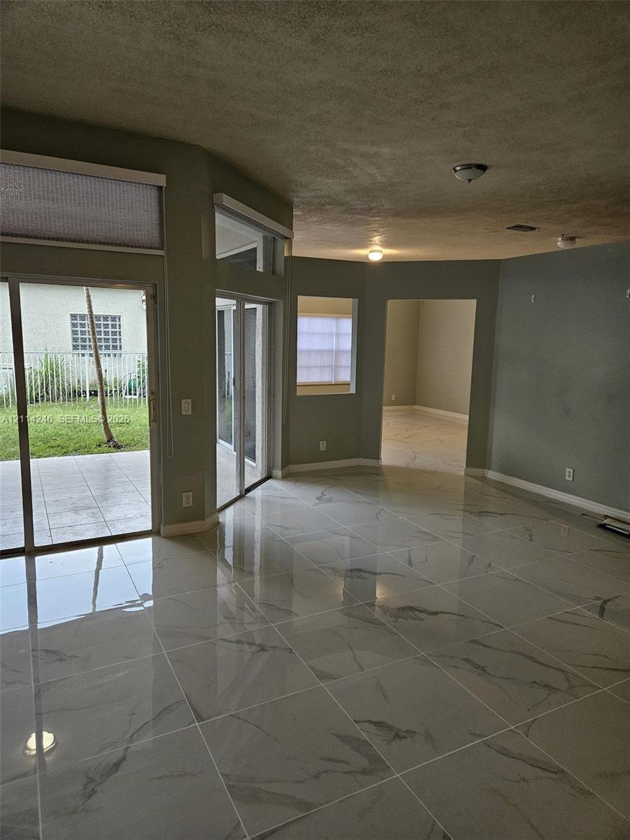 Large-format polished tile flooring, sliding glass doors, transom windows, and recessed ceiling lighting Large-format polished tile flooring, sliding glass doors, transom windows, and recessed ceiling lighting