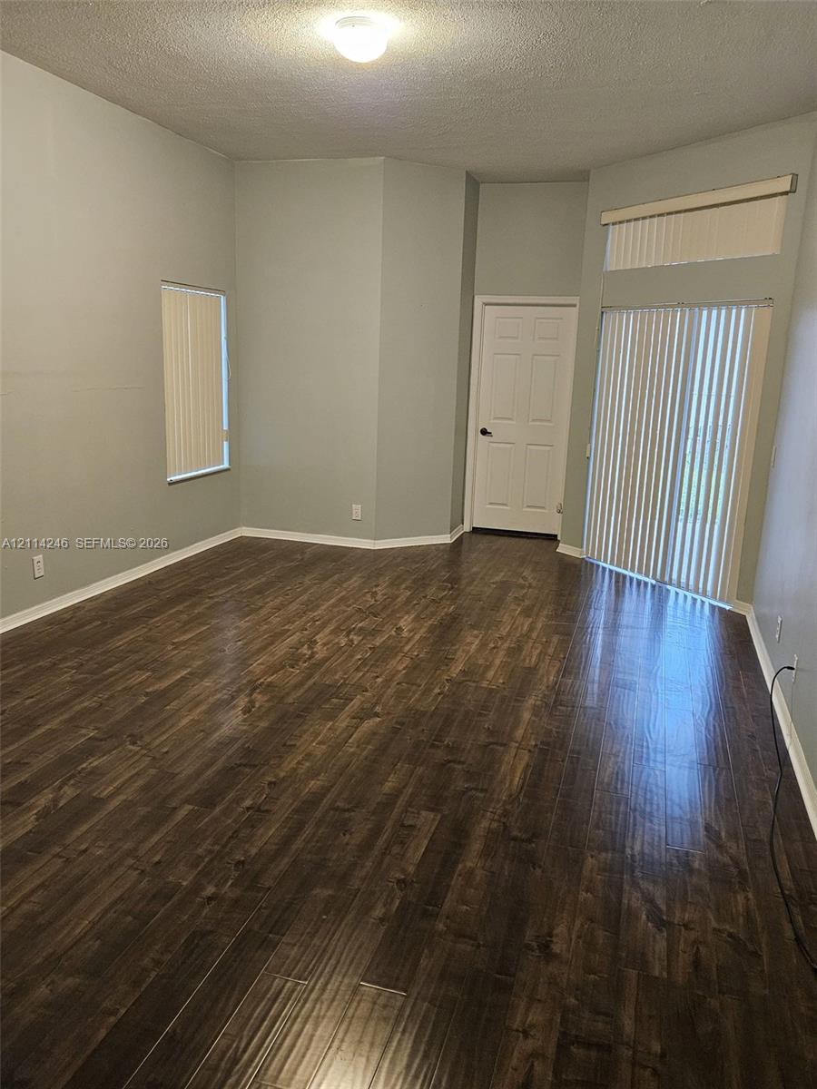 Wood-finish flooring, vaulted ceiling, sliding glass doors with transom window, and flush-mount ceiling lighting