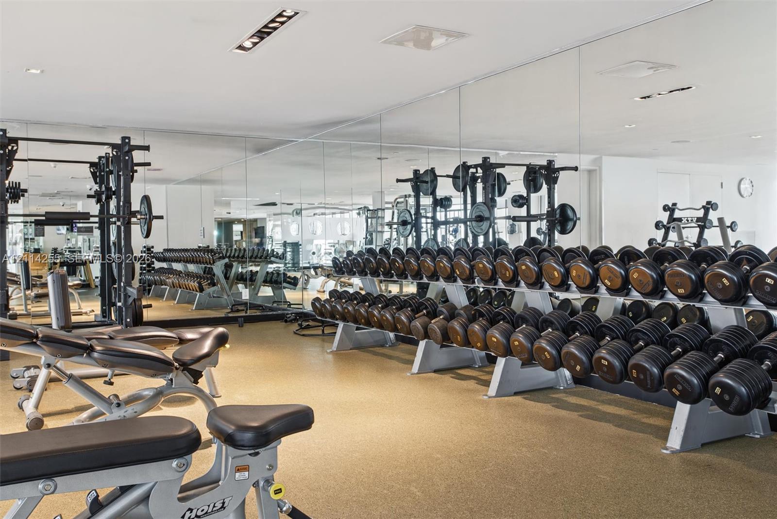 Fitness center featuring full-wall mirrors, recessed lighting, and durable rubberized flooring