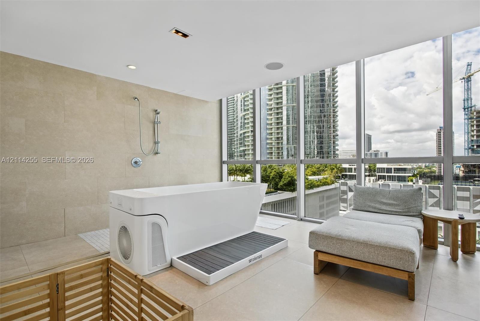 Floor-to-ceiling glass windows, stone-finish wall tile, large-format tile flooring, and integrated soaking tub with handheld shower fixture