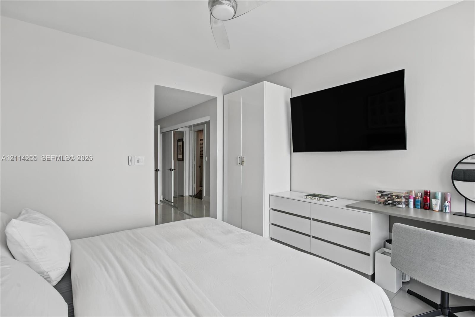 Room interior featuring high-gloss white built-in cabinetry, smooth-finish ceilings with a central fan, and neutral flooring