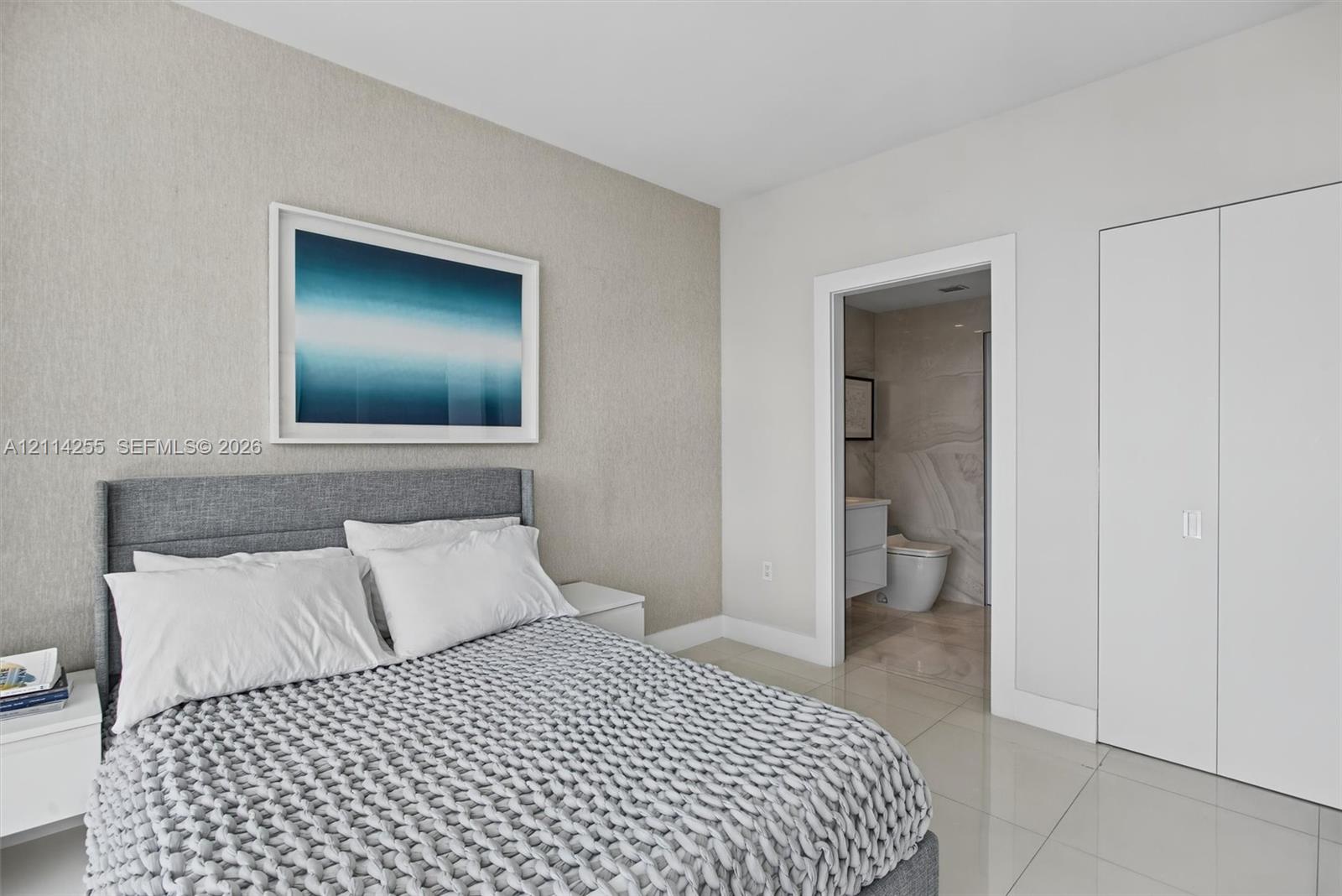 Neutral-toned textured accent wall featuring smooth-finish flooring, minimalist double-door closet cabinetry, and a clean-lined interior doorway