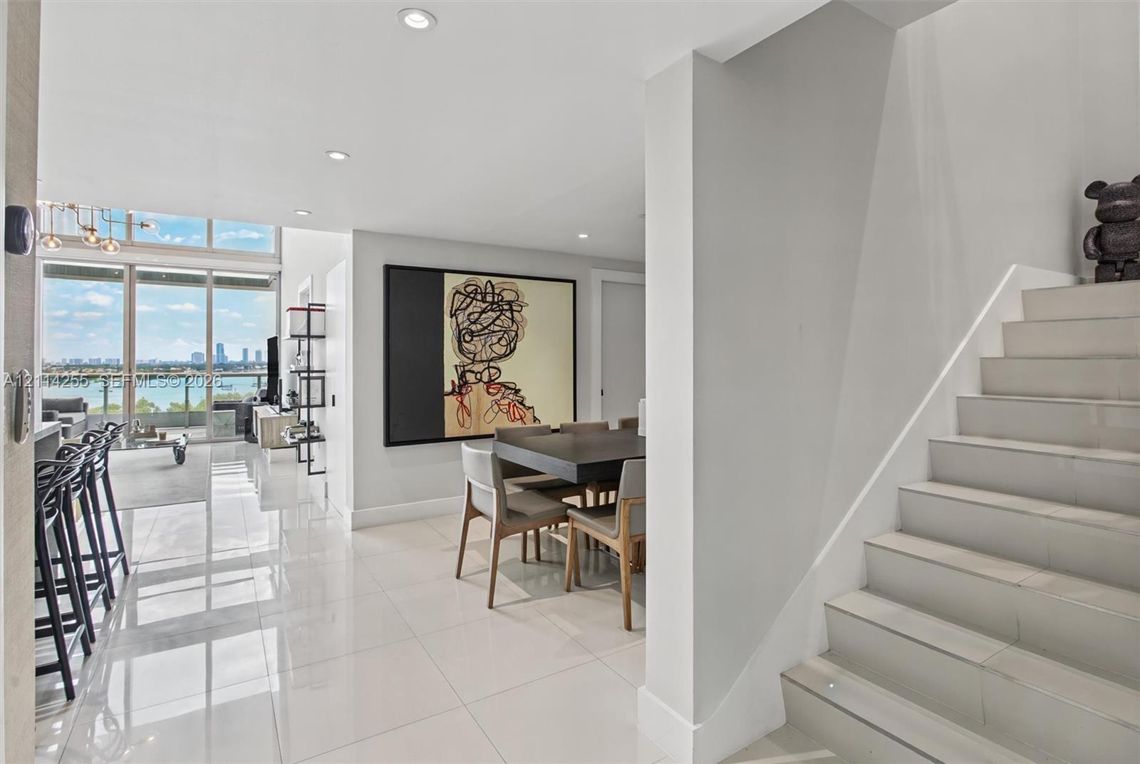 Polished tile flooring, floor-to-ceiling windows with water scenery, recessed lighting, and a staircase with tile treads