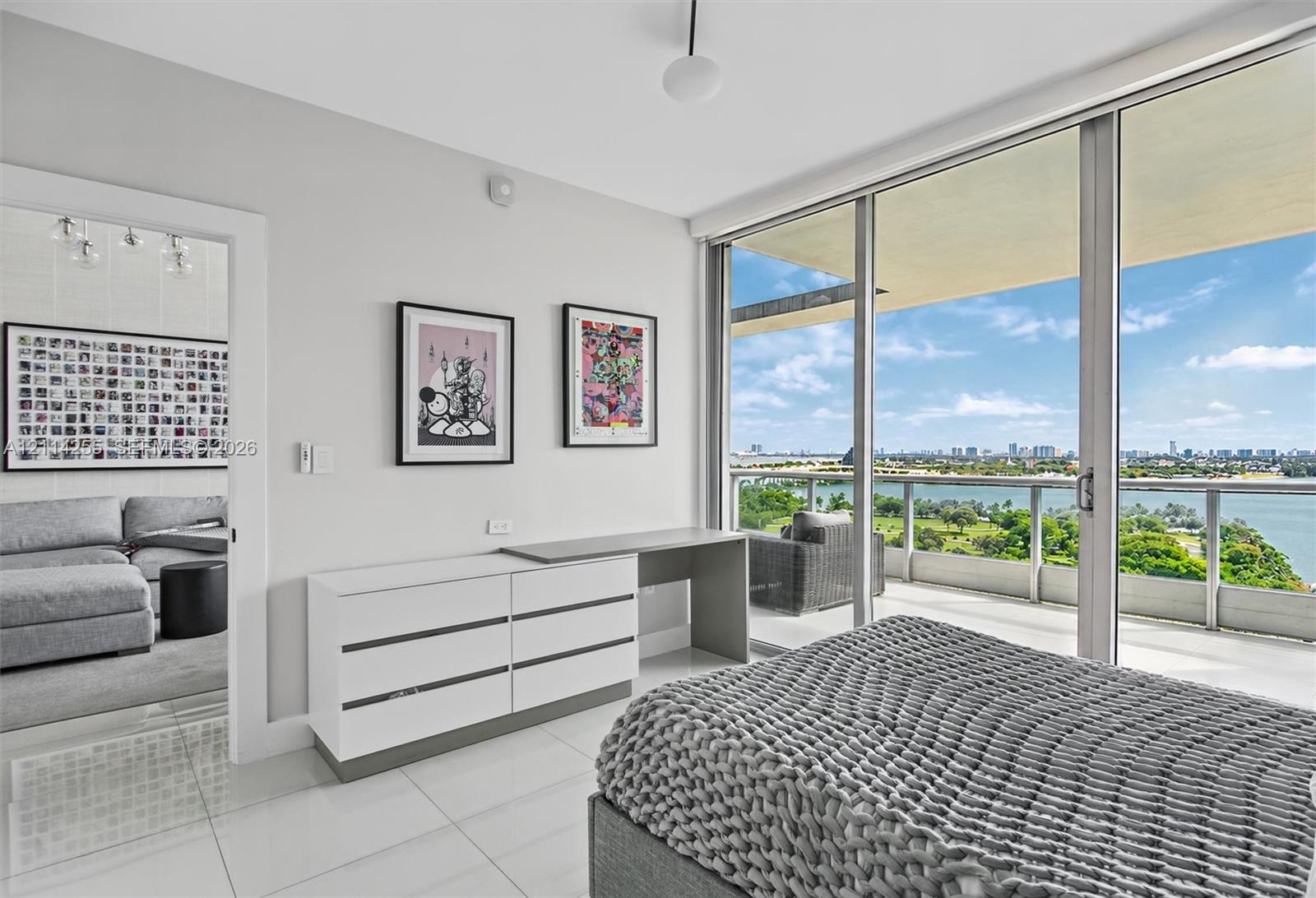 Floor-to-ceiling glass sliding doors, private balcony with metal railing, white tile flooring, and clean-lined interior finishes