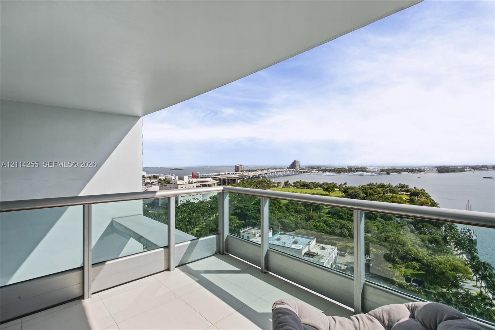 Covered balcony featuring tile flooring and a glass-paneled metal railing