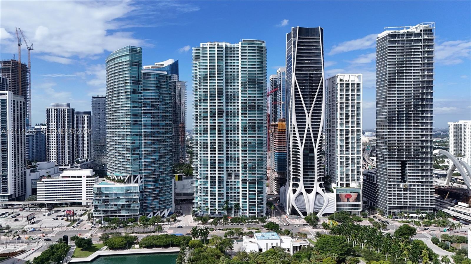 High-rise urban landscape featuring contemporary glass-clad skyscrapers, integrated structural lattice design, concrete and steel facades, and water-front proximity