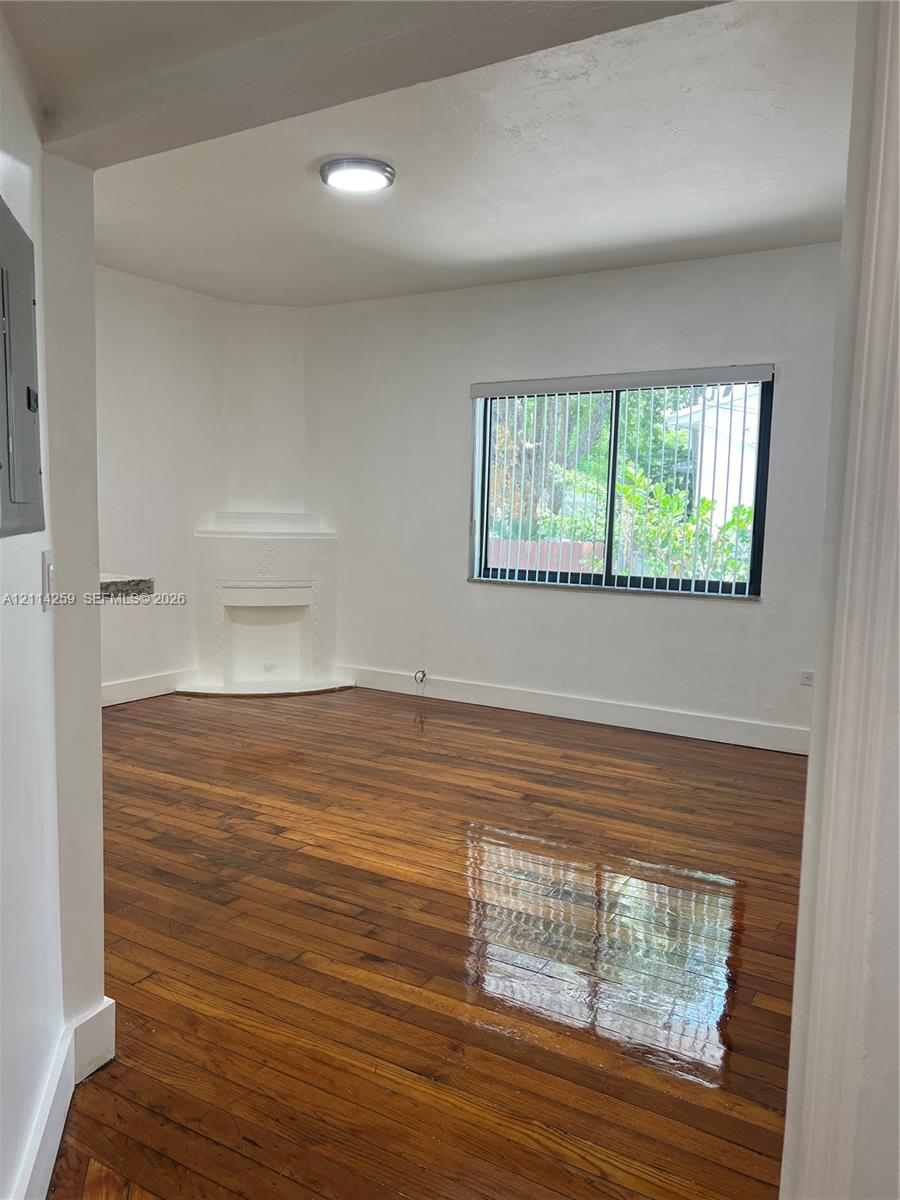 Interior space featuring wood-finish flooring, a corner fireplace mantel, a dual-pane horizontal sliding window, and flush-mount ceiling lighting
