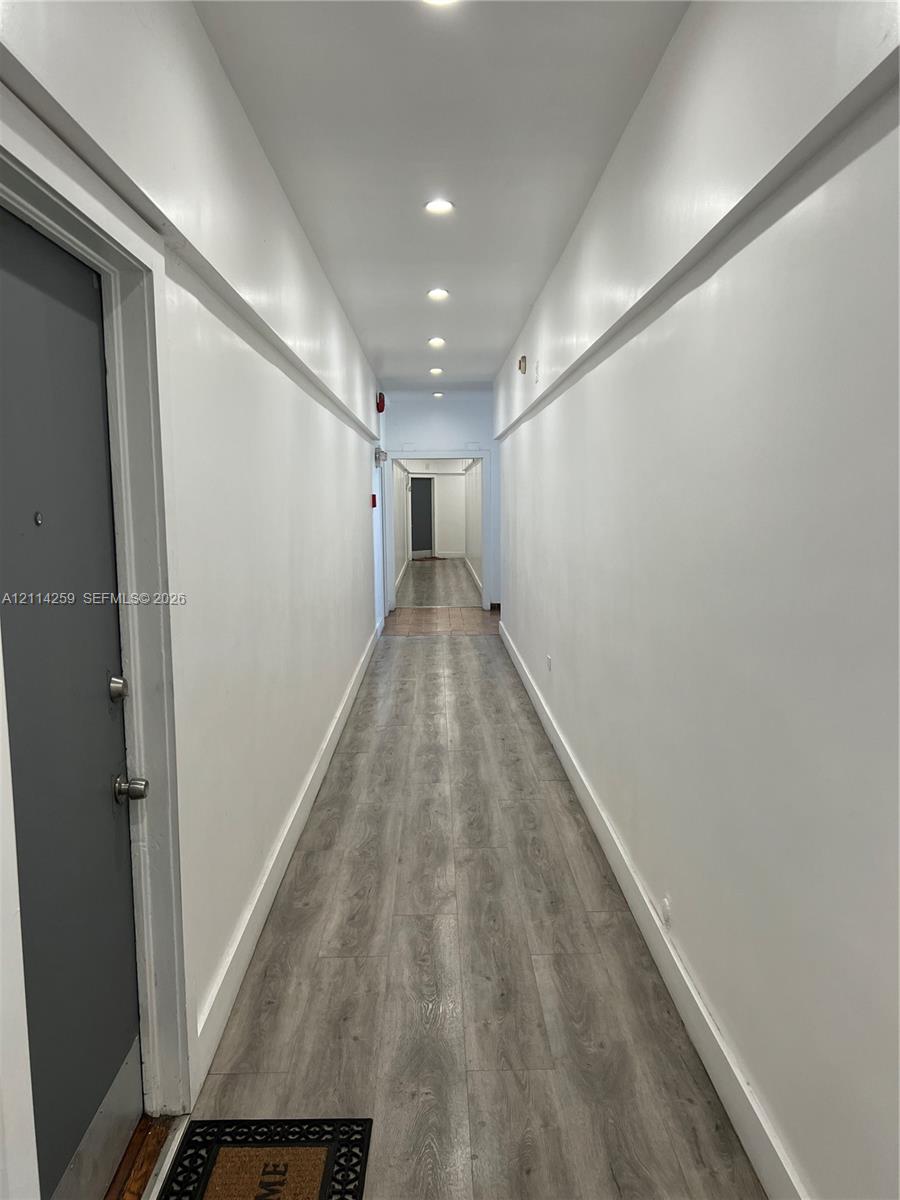 Hallway featuring wood-finish flooring, recessed lighting, and crisp white wall molding