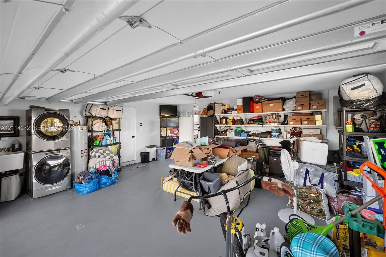 Garage space featuring finished floor, mounted wall shelving, and dedicated laundry area with stacked washer and dryer