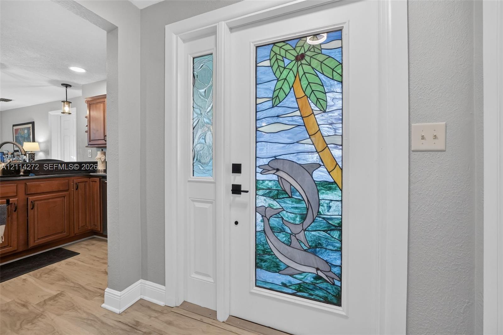 Entryway featuring a white door with a decorative stained glass insert, a matching side lite, matte black hardware, and wood-finish flooring