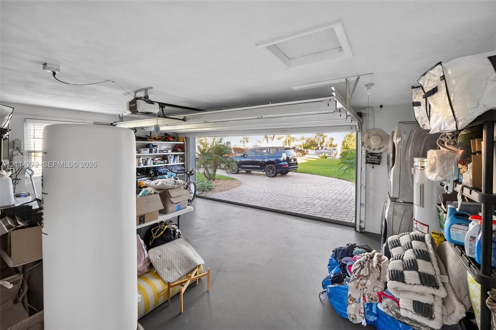 Enclosed garage featuring a concrete floor, built-in shelving, and an overhead automatic garage door opener