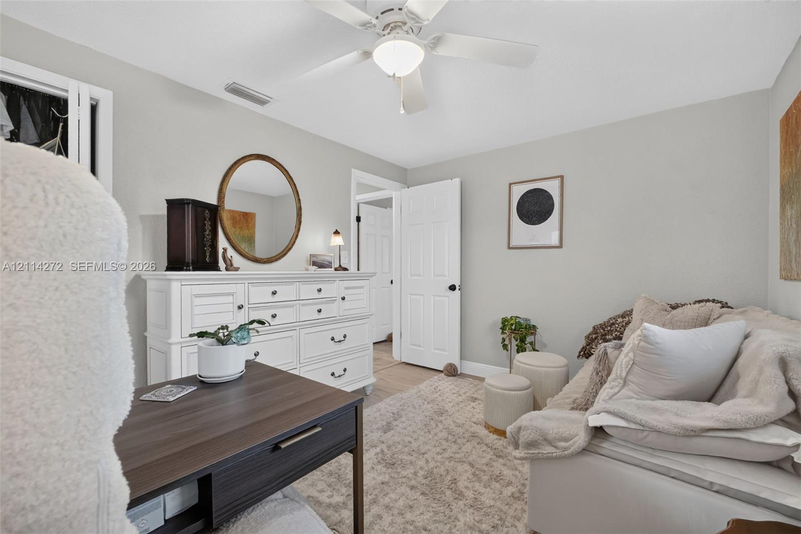 Room featuring neutral wall paint, a white four-blade ceiling fan with integrated lighting, and a six-panel interior door