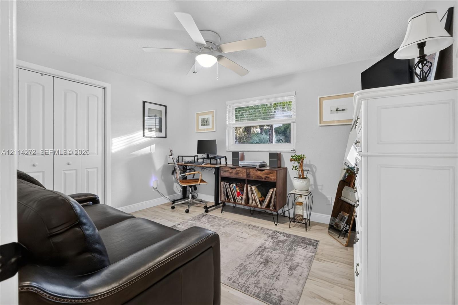 Room featuring wood-finish flooring, a white ceiling fan with integrated lighting, a horizontal sliding window, and bi-fold closet doors