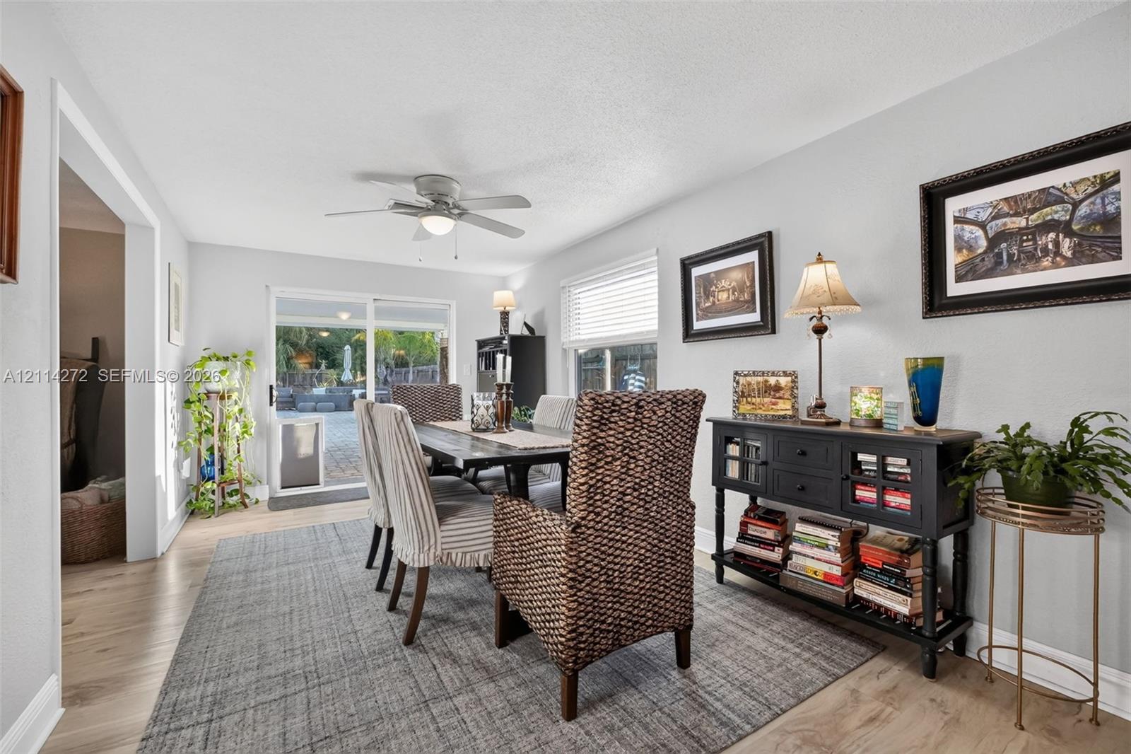 Dining area featuring wood-finish flooring, a ceiling fan with integrated lighting, and sliding glass doors