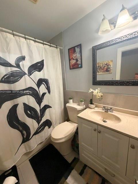 Bathroom featuring a white vanity cabinet with an integrated sink and countertop, two-light fixture, and a framed mirror