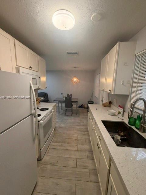 Kitchen featuring white shaker-style cabinetry, solid-surface countertops, wood-finish tile flooring, a stainless steel undermount sink, and a gooseneck faucet