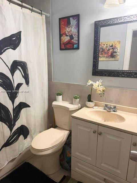 Bathroom featuring a vanity with shaker-style cabinetry, an integrated countertop with a rounded basin, a wall-mounted mirror with an ornate frame, and tile wainscoting