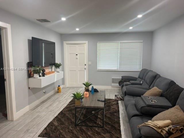 Interior room featuring wood-finish tile flooring, recessed ceiling lighting, and a white wall-mounted media console