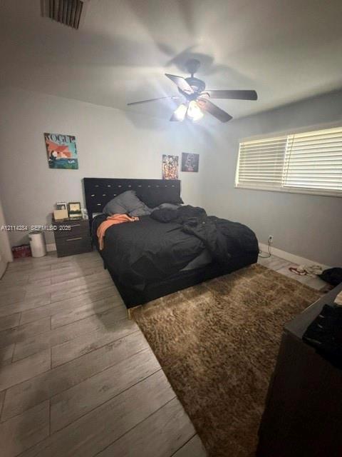 Room featuring wood-finish flooring, a multi-blade ceiling fan with integrated lighting, and horizontal window blinds