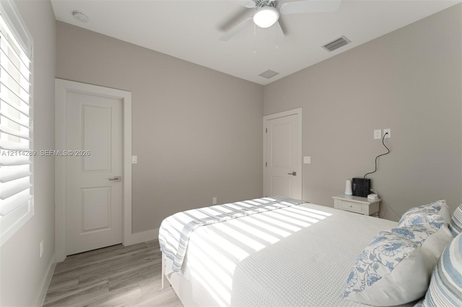 Neutral interior featuring wood-finish flooring, two-panel interior doors, plantation shutters, and a ceiling fan with integrated lighting