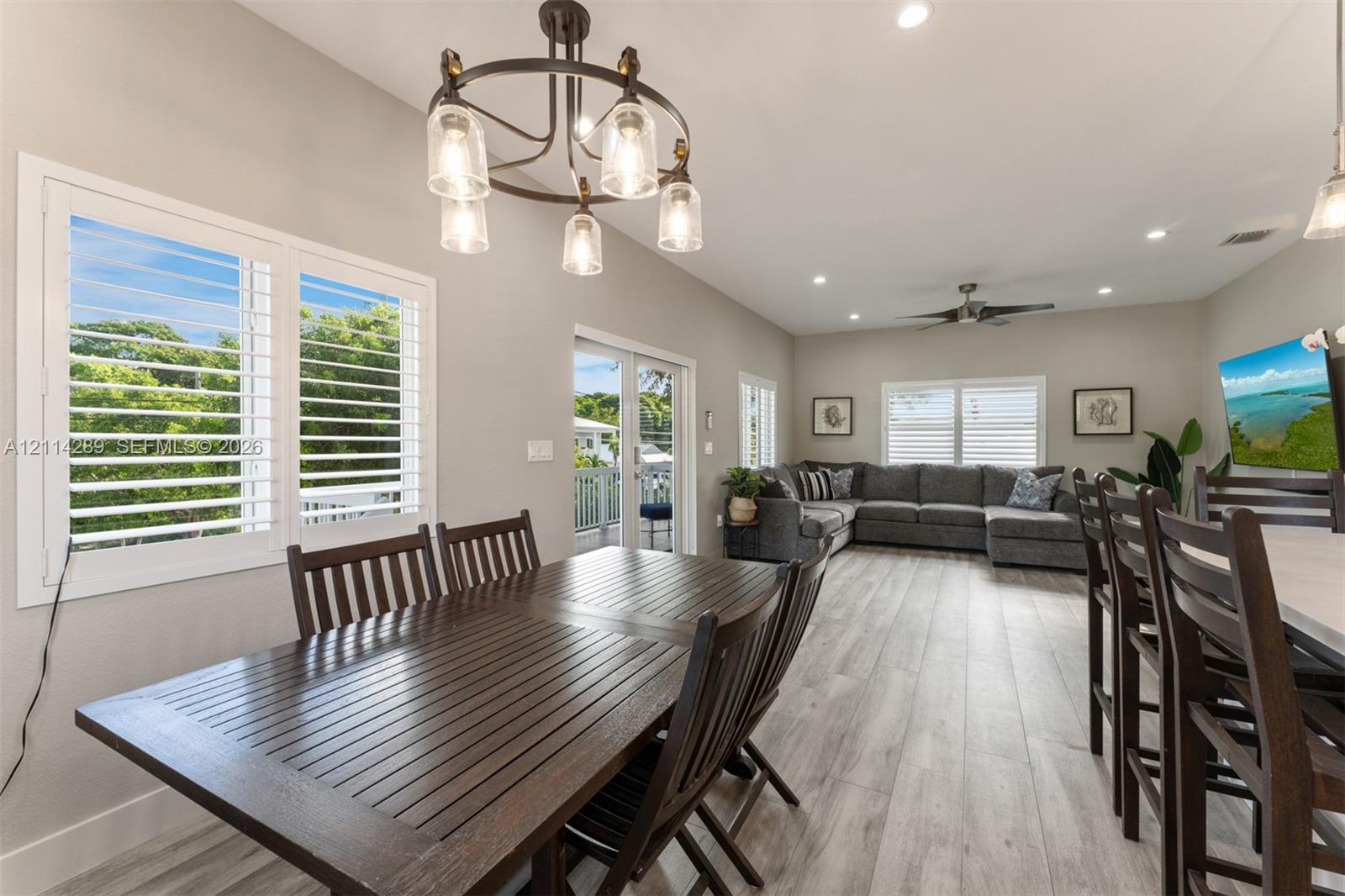 Open floor plan featuring wood-finish flooring, recessed lighting, plantation shutters, and a multi-light chandelier