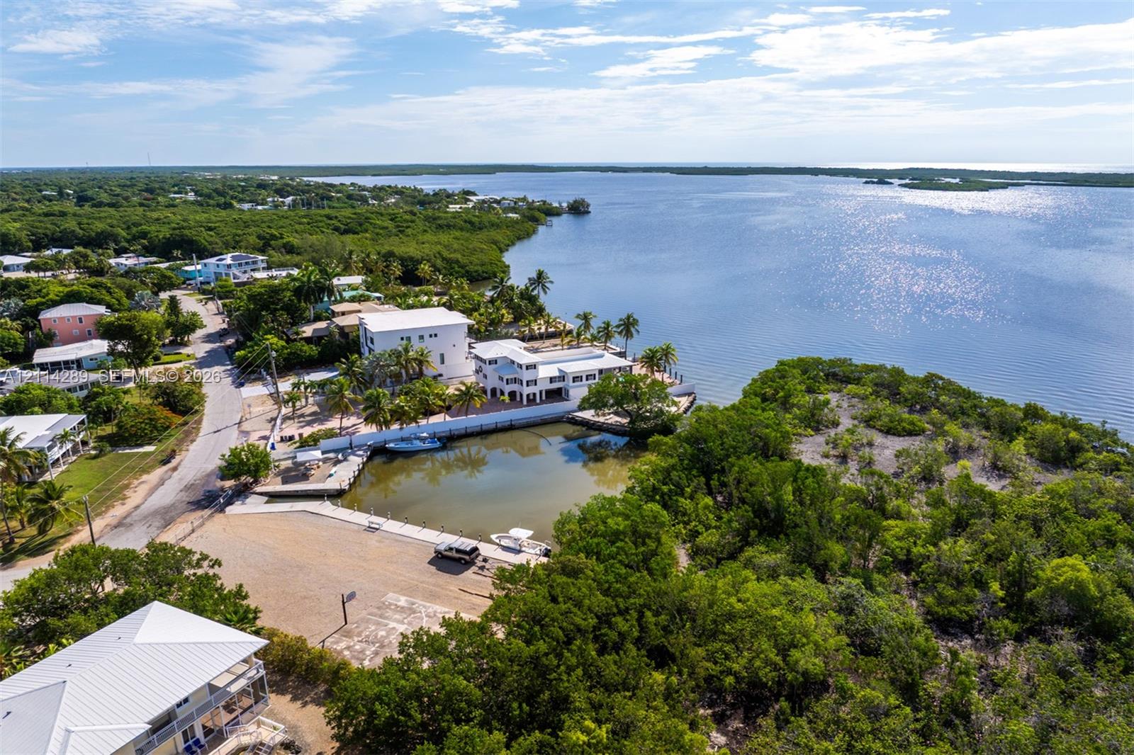 Waterfront property featuring a private boat basin, concrete dockage, paved driveway, and multiple stories of exterior balcony space